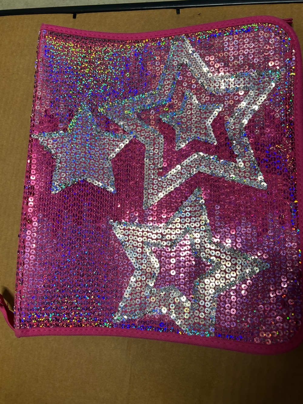Hot pink, 3 ring binder notebook that zips up and has sequins on the front.